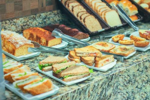 a buffet of different types of sandwiches and pastries at Pousada Acqua Infinity PISCINA CLIMATIZADA PÉ NA AREIA in Bertioga