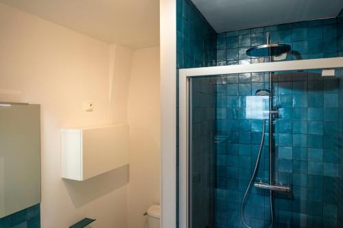 La salle de bains est pourvue d'une douche avec du carrelage bleu. dans l'établissement Charmant appartement 4 personnes en centre-ville, à Caen