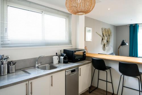 une cuisine avec un évier et un micro-ondes dans l'établissement Charmant appartement 4 personnes en centre-ville, à Caen