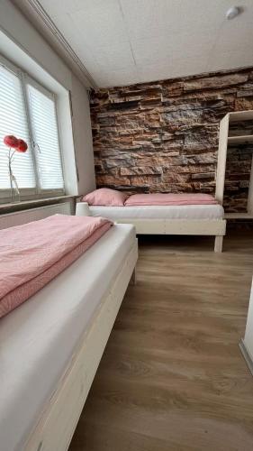 two beds in a room with a brick wall at Highway Ferienwohnung in Preußisch Oldendorf