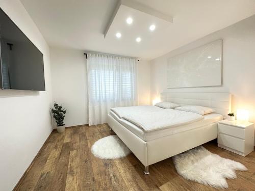 Habitación blanca con cama y ventana en Spacious Green Cosy Apartment near Maribor, en Pesnica pri Mariboru
