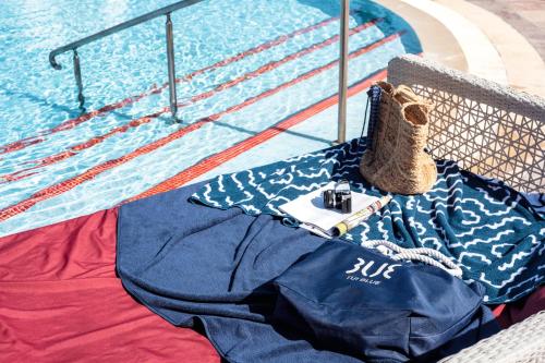 a table next to a swimming pool with a bag and camera at TUI BLUE Scheherazade Adults Only - All Inclusive in Sousse