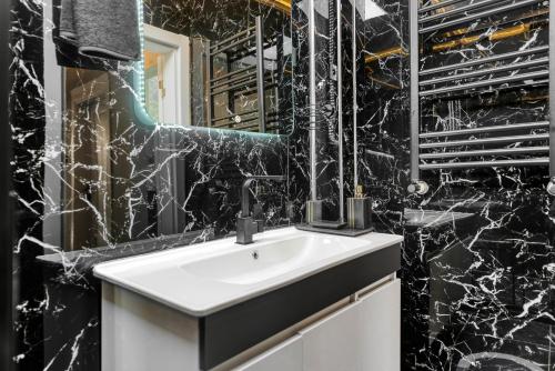 baño con lavabo blanco y paredes de mármol negro. en Nil Denis Palace, en Estambul