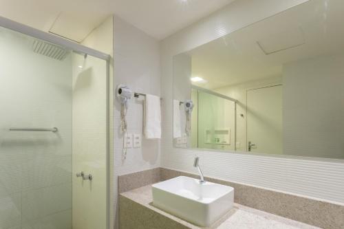 a white bathroom with a sink and a mirror at Flat Edf Golden Beach in Recife