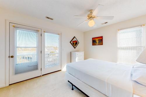 1 dormitorio con cama blanca y ventanas en Flip Flop Inn, en Holden Beach