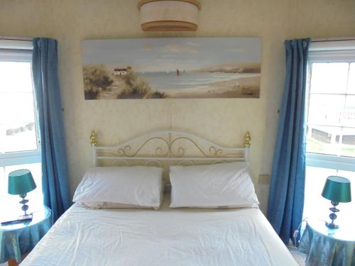 a bedroom with a bed with blue curtains and a painting at Golden palm : Vogue 6 Berth, Central Heated, Enclosed Veranda in Chapel Saint Leonards