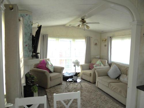 a living room with two couches and two windows at Golden palm : Vogue 6 Berth, Central Heated, Enclosed Veranda in Chapel Saint Leonards