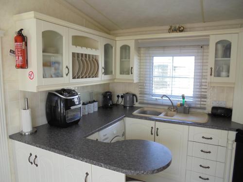 a kitchen with white cabinets and a sink at Golden palm : Vogue 6 Berth, Central Heated, Enclosed Veranda in Chapel Saint Leonards
