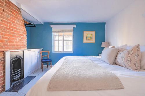 a blue bedroom with a bed and a fireplace at Sage Cottage in Ditchling