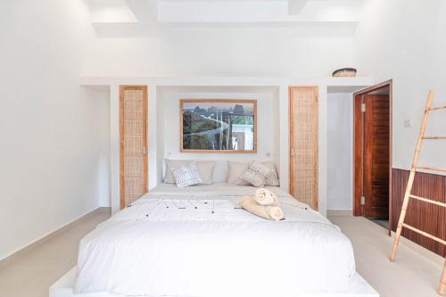 a bedroom with a large white bed with a dog laying on it at Sunset Villa in Munggu