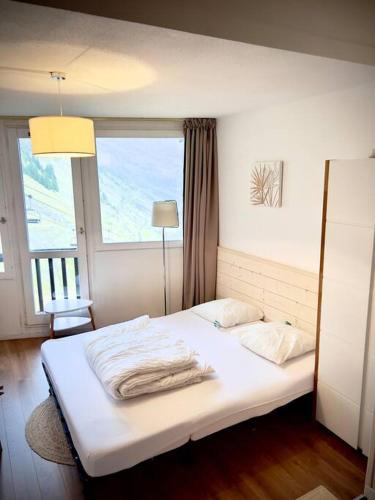 un lit blanc dans une chambre avec une fenêtre dans l'établissement Studio centre vue montagne SNOW AVORIAZ, à Morzine