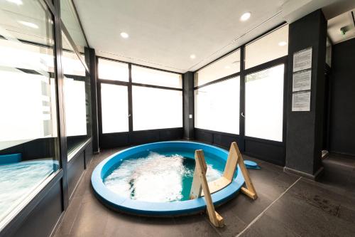 - une grande baignoire bleue dans une chambre avec fenêtres dans l'établissement Filo Hotel Wellness & Spa, à Gheorgheni