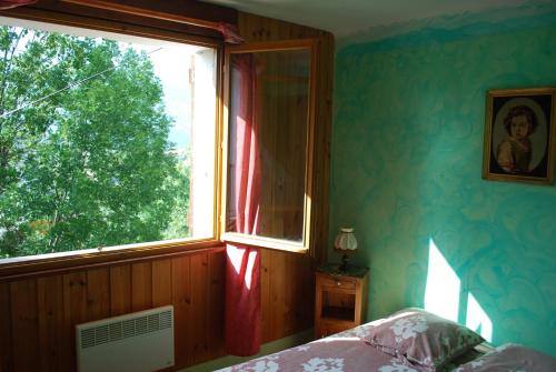 - une chambre avec une fenêtre, un lit et un arbre dans l'établissement Le Clos Du Berger, au Sauze