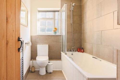 a bathroom with a toilet and a bath tub at Sage Cottage in Ditchling