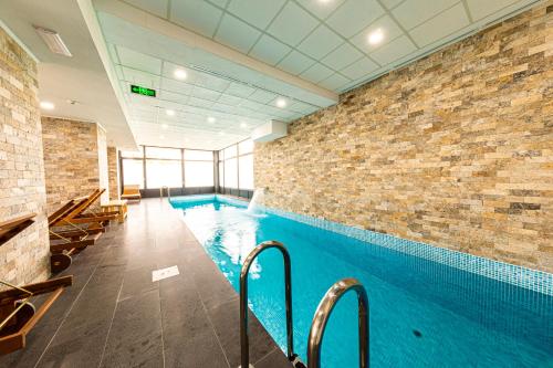 a large swimming pool with a brick wall at Filo Hotel Wellness & Spa in Gheorgheni