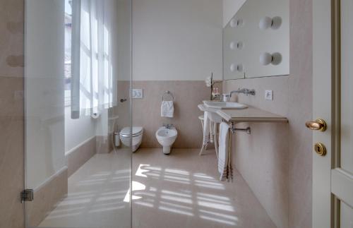 Baño blanco con aseo y lavamanos en Rambaldi Apartments Casa nr 6 with shared Terrace, en Bardolino