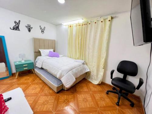um quarto com uma cama, uma secretária e uma cadeira em Hermoso apartamento acogedor-cocina wi-fi 500MB em Bogotá