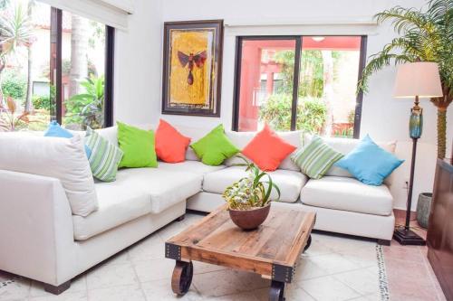 a living room with a white couch with colorful pillows at Villa Familiar en exclusivo condominio playacar in Playa del Carmen