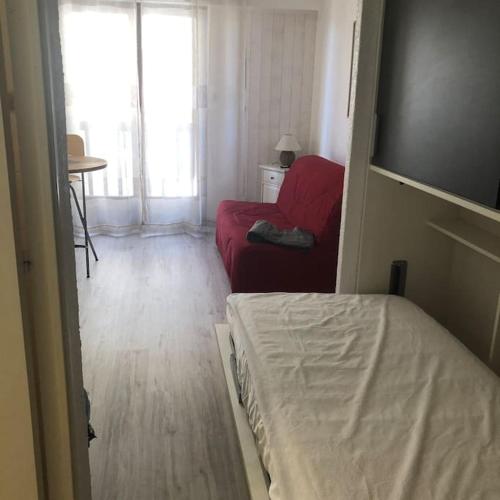 une chambre avec un lit et un canapé rouge dans l'établissement Studio cosy cœur de Font Romeu, à Font-Romeu-Odeillo-Via