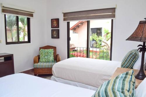 a bedroom with two beds and two chairs and a window at Villa Familiar en exclusivo condominio playacar in Playa del Carmen