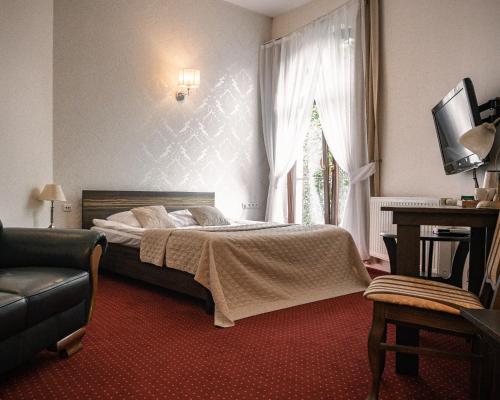 a bedroom with a bed and a window and a couch at Hotel Korona in Rybnik