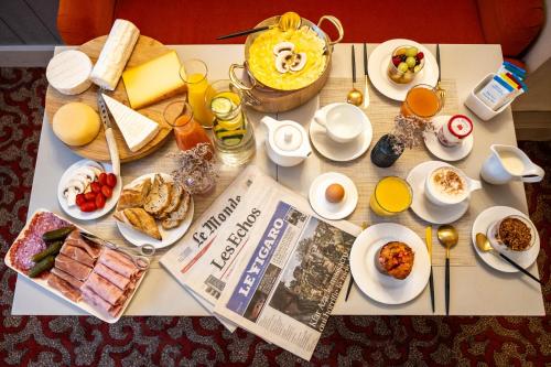 uma mesa coberta com alimentos de pequeno-almoço e um jornal em Hotel Residence Foch em Paris