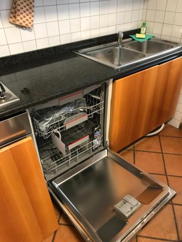 een lege vaatwasser in een keuken naast een wastafel bij DOLOMITI HOUSE STUBE in Fiera di Primiero