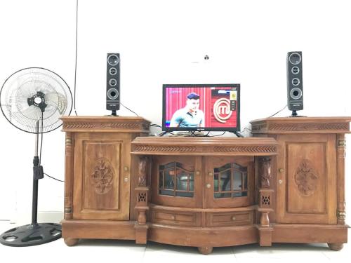 - un centre de divertissement en bois avec un ventilateur et une télévision dans l'établissement Homestay Lavender C6 Palembang, à Palembang