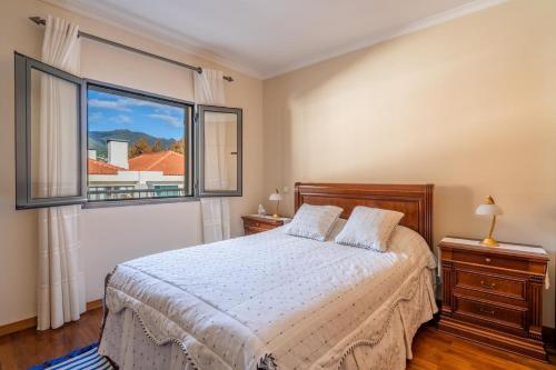 ein Schlafzimmer mit einem Bett und einem großen Fenster in der Unterkunft Harmonia Apartment by Atlantic Holiday in Machico