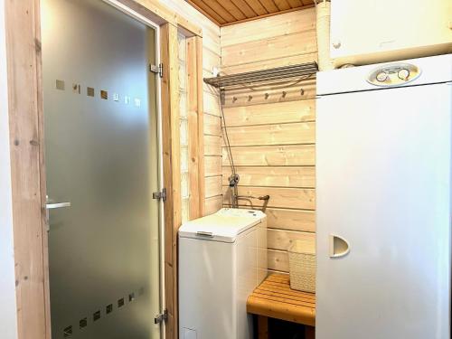 a small bathroom with a refrigerator and a wooden wall at Hietavilla Aurora in Ruka