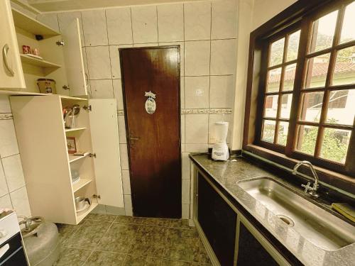 a kitchen with a sink and a wooden door at Condomínio Fazenda Garatucaia in Angra dos Reis