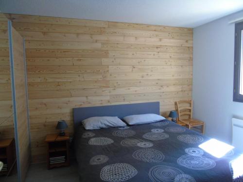 - une chambre avec un lit et un mur en bois dans l'établissement Appartement 3 pièces, proche télésiège, équipements modernes - FR-1-561-110, à Modane