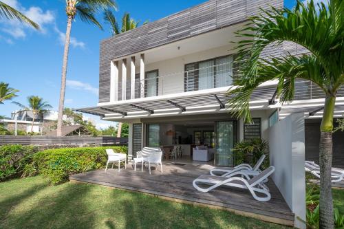 a house with a deck with chairs and palm trees at VILLA PIEDS DANS L'EAU - GRAND BAIE in Grand-Baie