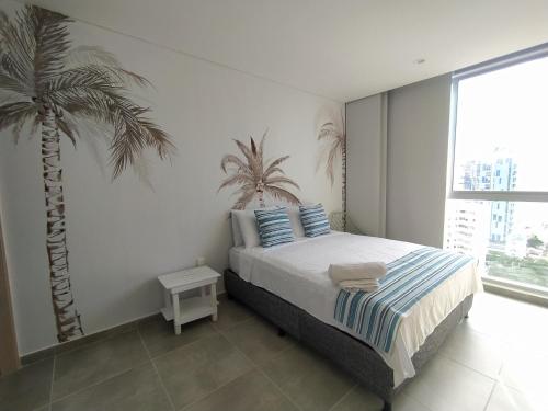 a bedroom with a bed and a palm tree at Exclusivo Apartamento Frente al mar in Gaira