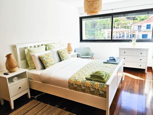 ein weißes Schlafzimmer mit einem Bett und einem Fenster in der Unterkunft Machico Oasis - Mountainview in Machico