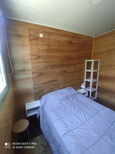 1 dormitorio con 1 cama y pared de madera en la mansion, en La Esmeralda