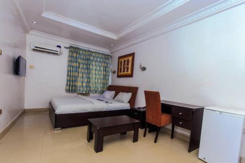 Habitación pequeña con cama, escritorio y escritorio. en BEN AUTO Hotel en Lagos