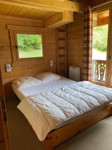 1 dormitorio con 1 cama en una cabaña de madera en Les Oiseaux Bleus, en Morillon