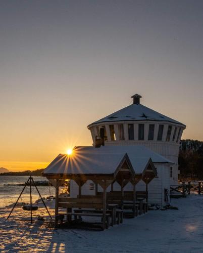a lighthouse on the beach with the sun setting at Norwegian Wild in Vangsvik