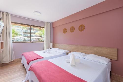 two beds in a room with pink walls at Praia Muro Alto paradisíaco, Flat de 2 quartos. in Porto De Galinhas