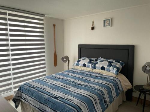 1 dormitorio con 1 cama con manta azul y blanca en Concon Depto Costa de Montemar vista insuperable!, en Concón