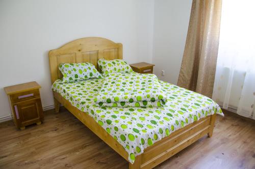 a bedroom with a bed with a green and white comforter at Vila Bucovina in Ciocăneşti