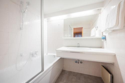 ein weißes Badezimmer mit einem Waschbecken und einem Spiegel in der Unterkunft Batzenhäusl in Seefeld in Tirol
