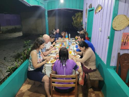 un grupo de personas sentadas en una mesa comiendo comida en CANTO DOS PASSAROS, en Manaus
