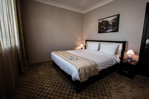 a bedroom with a large bed with two lamps on it at Sara Palace Apartments- family only in Kuwait