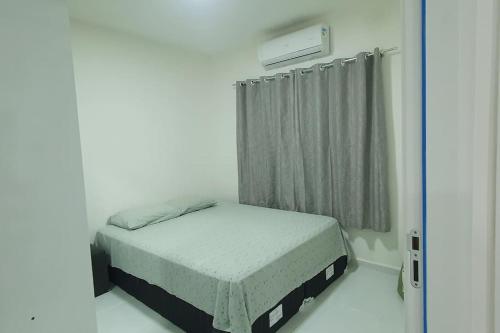 ein kleines Bett in einem weißen Zimmer mit Fenster in der Unterkunft Apartamento no Condomínio Roma com estacionamento in Pôrto Santana