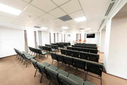 a lecture hall with green chairs and a screen at Filo Hotel Wellness & Spa in Gheorgheni