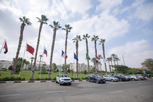 una fila de autos estacionados en un estacionamiento con palmeras en Le Passage Cairo Hotel & Casino, en El Cairo