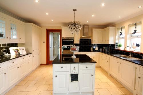 a large kitchen with white cabinets and black counter tops at Ayrs and Graces - Luxury Bed and Breakfast in Ayr