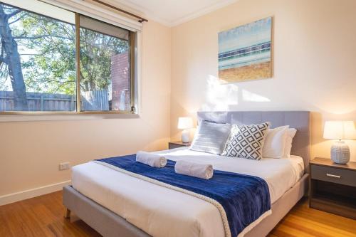 Un dormitorio con una cama grande y una ventana en Nunawading Beautiful 3br Housedeckingcourtyard, en Nunawading